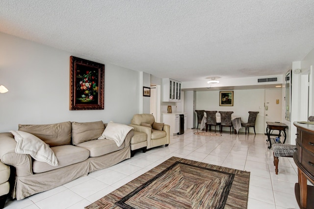 living room with bar area, visible vents, a textured ceiling, and light tile patterned floors