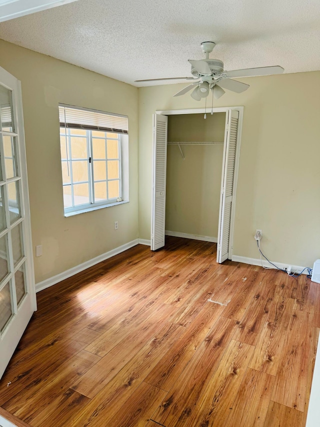 unfurnished bedroom with a textured ceiling, light hardwood / wood-style flooring, ceiling fan, and a closet