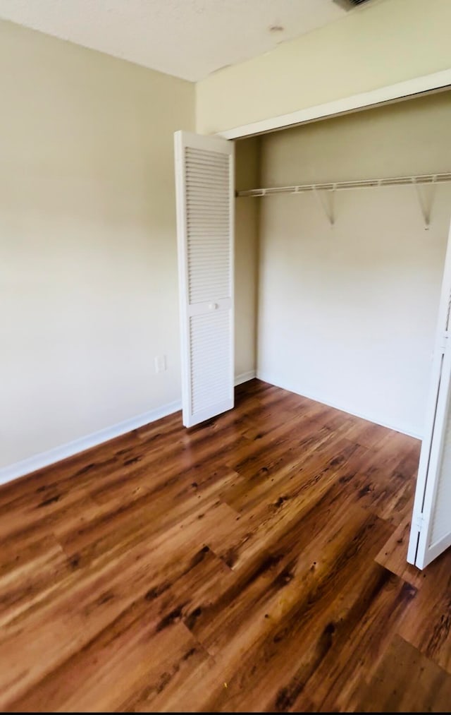 unfurnished bedroom featuring a closet and hardwood / wood-style flooring