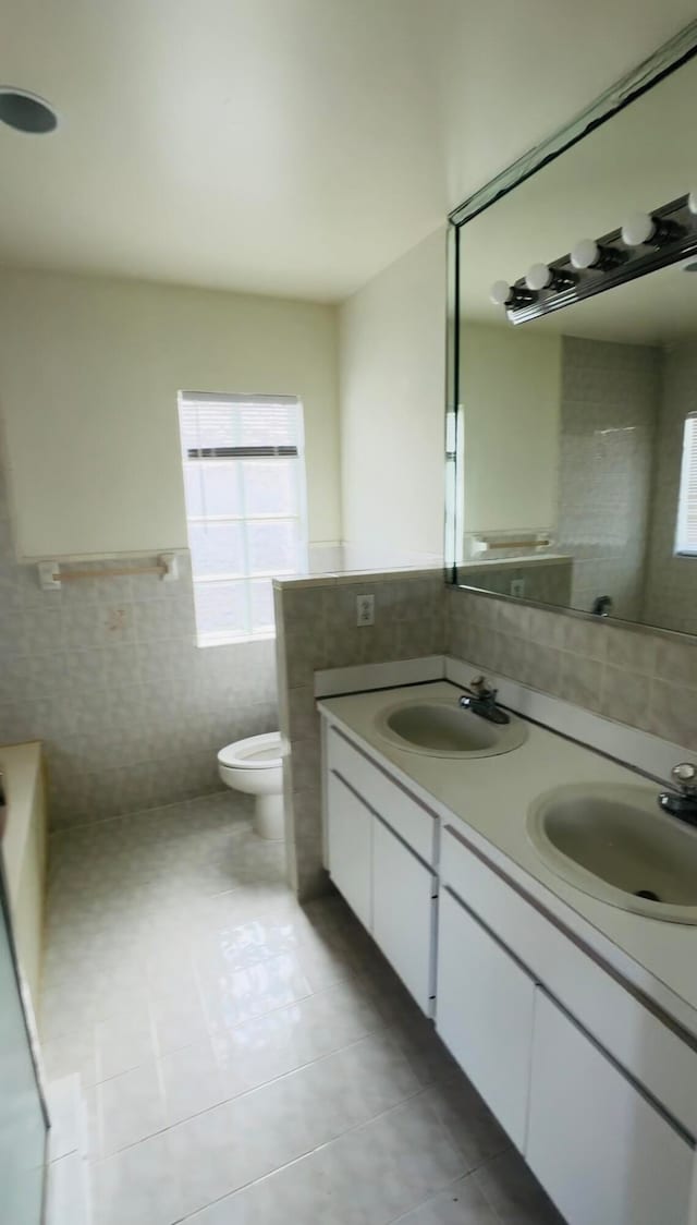 bathroom featuring tile patterned flooring, tile walls, toilet, and vanity