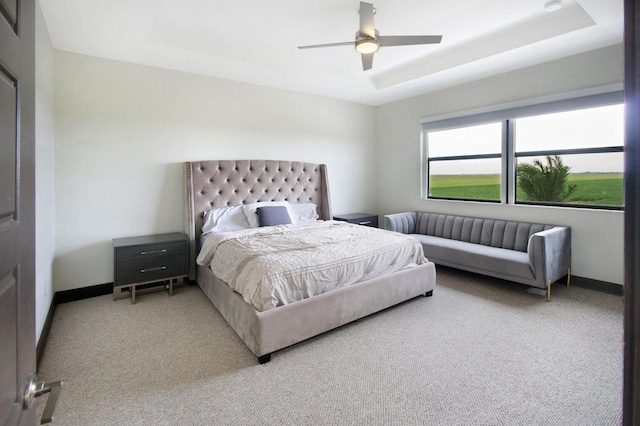 carpeted bedroom featuring a tray ceiling and ceiling fan