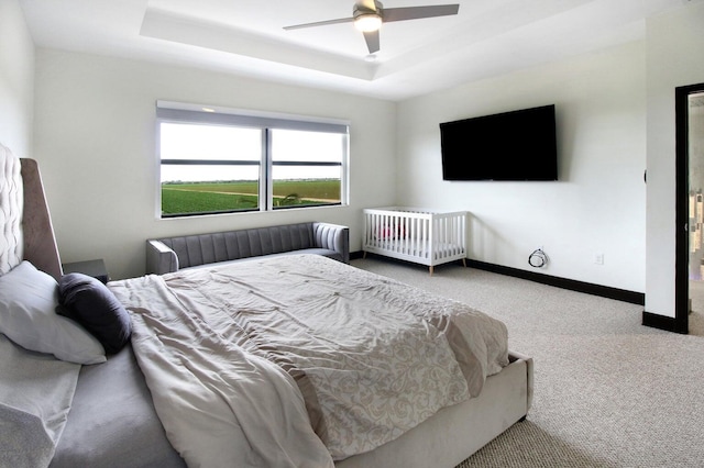 bedroom with ceiling fan, a raised ceiling, and carpet flooring