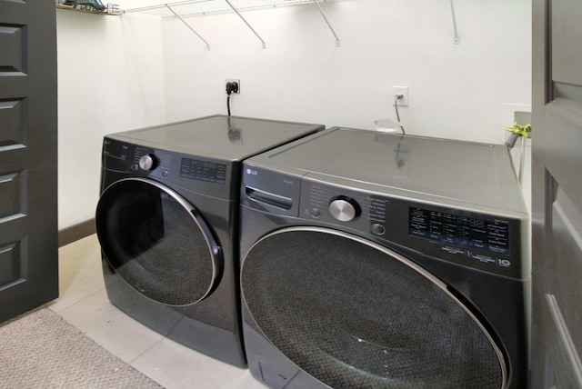 clothes washing area with washing machine and dryer and light tile patterned floors