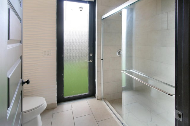 bathroom with toilet, walk in shower, and tile patterned flooring