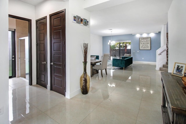 hallway with tile patterned flooring and an inviting chandelier