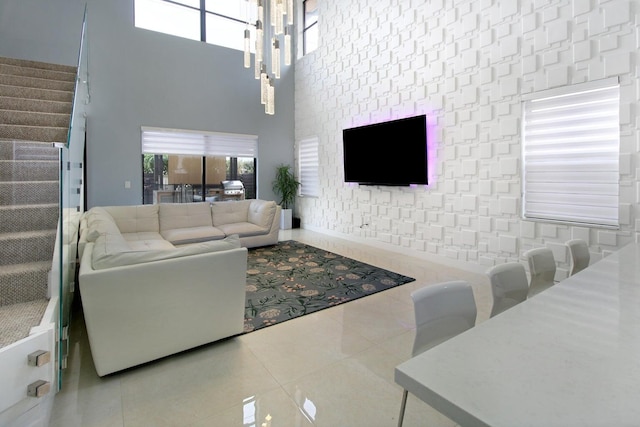 tiled living room featuring a wealth of natural light, an inviting chandelier, and a towering ceiling