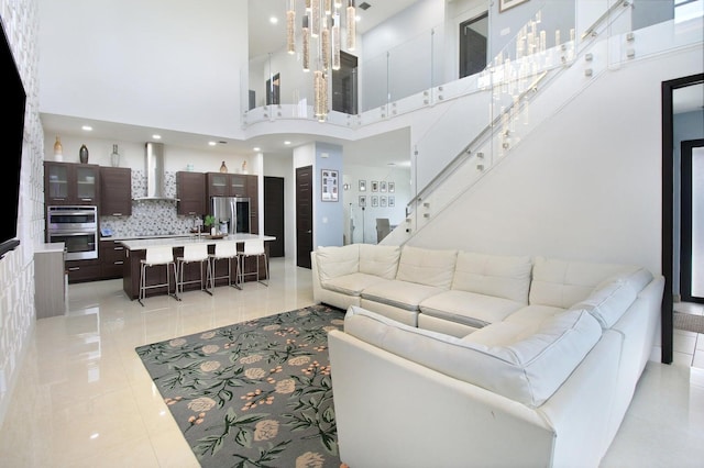 tiled living room featuring a towering ceiling, a notable chandelier, and sink