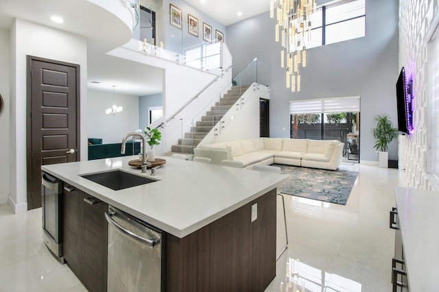 kitchen with dishwasher, dark brown cabinetry, sink, light tile patterned floors, and a towering ceiling