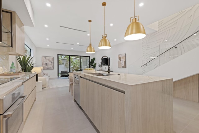 kitchen with decorative light fixtures, light stone countertops, an island with sink, and sink