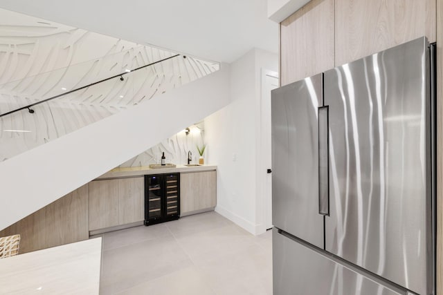 kitchen featuring light brown cabinetry, beverage cooler, stainless steel refrigerator, and sink