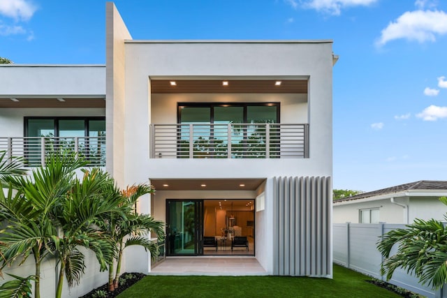 back of property with a yard, a patio, and a balcony