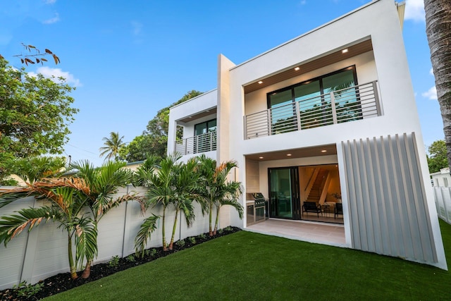 back of house with a balcony, a yard, and a patio area