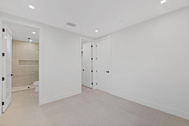 unfurnished bedroom with light tile patterned floors and ensuite bath