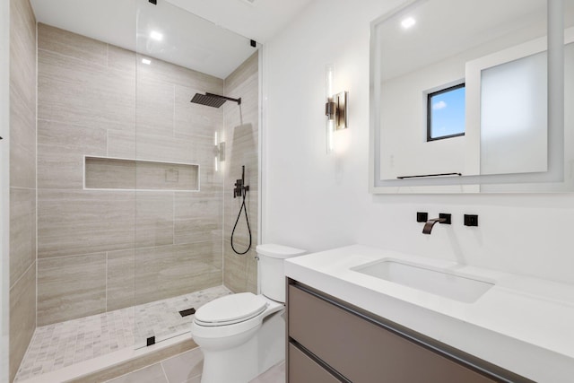 bathroom featuring vanity, toilet, a tile shower, and tile patterned floors