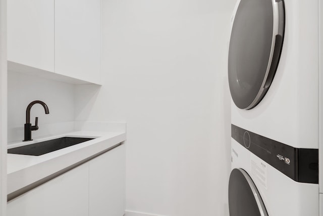 clothes washing area with sink, cabinets, and stacked washer / drying machine