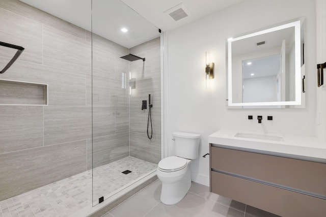 bathroom with vanity, toilet, tiled shower, and tile patterned floors