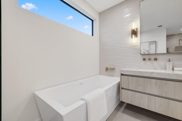 bathroom featuring vanity, a bath, and tile walls