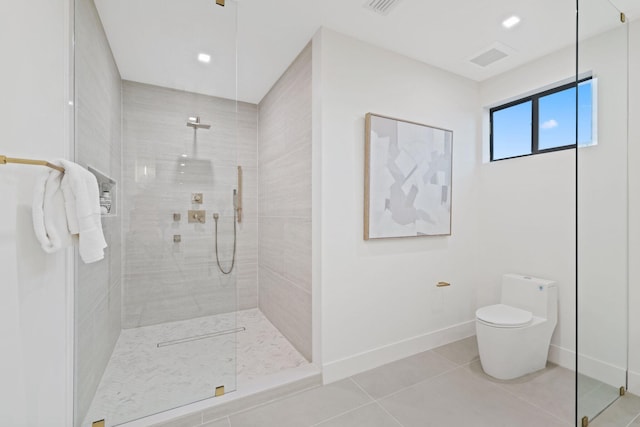 bathroom with tiled shower, toilet, and tile patterned floors