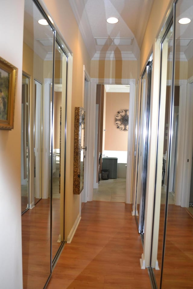 corridor with hardwood / wood-style floors and ornamental molding