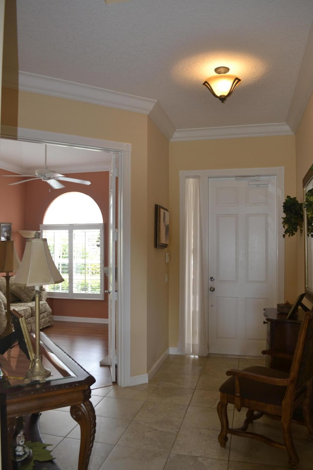 entryway with ceiling fan, light tile patterned floors, and crown molding