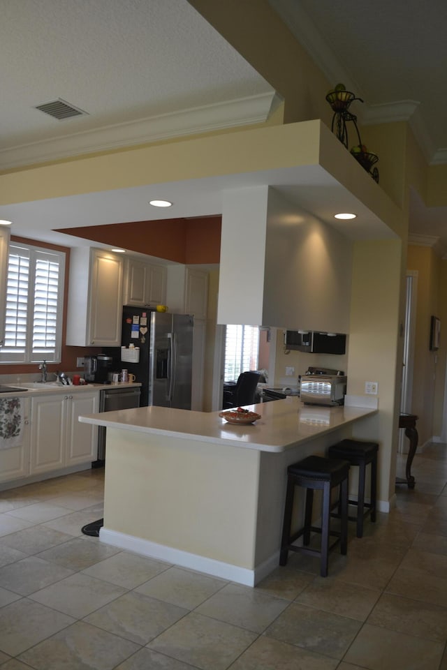 kitchen featuring a wealth of natural light, kitchen peninsula, a kitchen breakfast bar, and stainless steel appliances