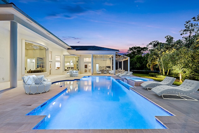 pool at dusk with an in ground hot tub, a patio, and ceiling fan