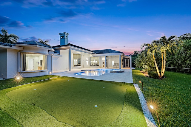 pool at dusk with a lawn and a patio