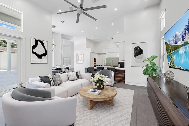 tiled living room with ceiling fan and a towering ceiling