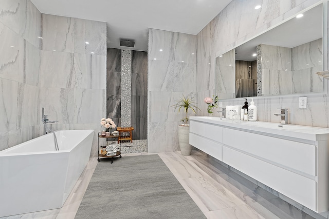 bathroom featuring separate shower and tub, vanity, and tile walls