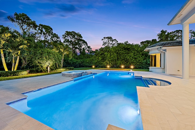 pool at dusk with an in ground hot tub and a patio