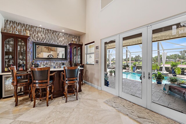 bar featuring a dry bar, a high ceiling, baseboards, and french doors