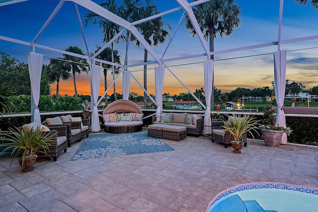 pool at dusk with a patio area, glass enclosure, and outdoor lounge area