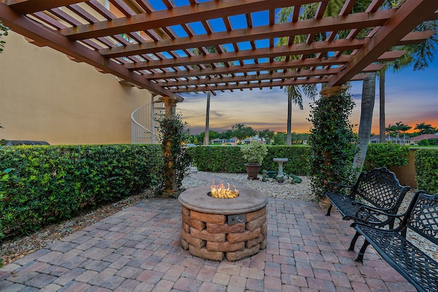 patio terrace at dusk with an outdoor fire pit and a pergola