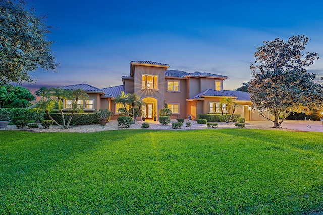 mediterranean / spanish house featuring a lawn and stucco siding