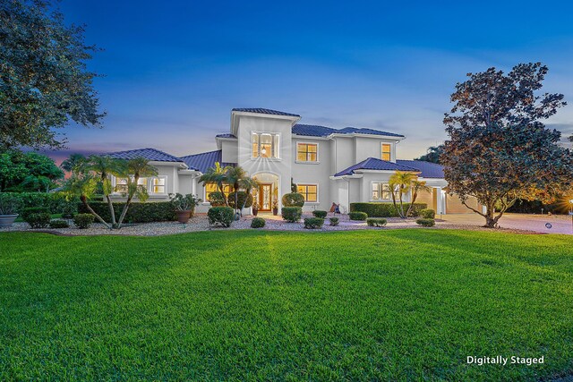 view of front of house featuring a tiled roof, a front lawn, and stucco siding