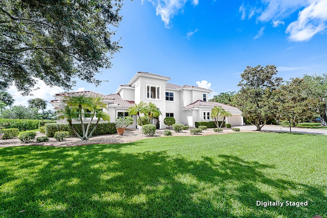 mediterranean / spanish home with stucco siding, a tiled roof, and a front yard