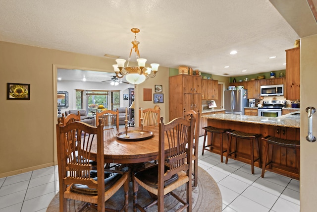 tiled dining area with ceiling fan with notable chandelier and a textured ceiling