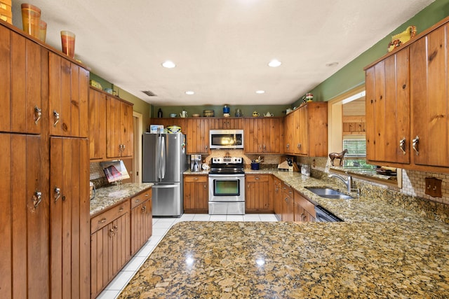 kitchen featuring light stone countertops, stainless steel appliances, decorative backsplash, sink, and light tile patterned floors