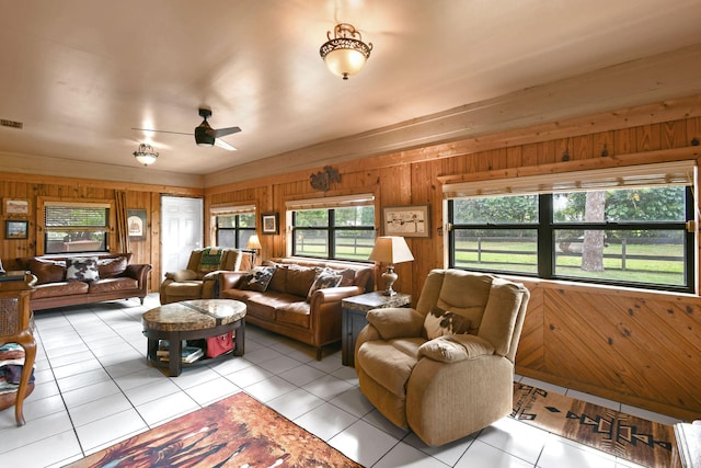 living room featuring ceiling fan, a healthy amount of sunlight, wood walls, and light tile patterned flooring