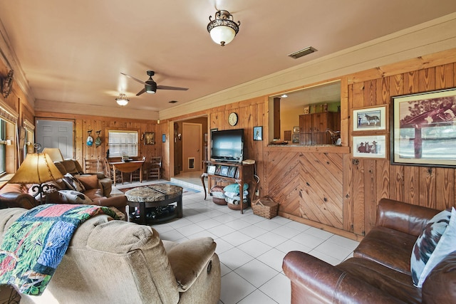 living room featuring ceiling fan, light tile patterned floors, and wood walls