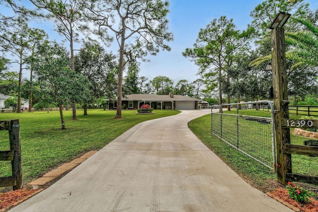 ranch-style house with an attached garage, fence, a front yard, driveway, and a gate