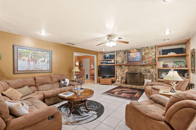 tiled living room with ceiling fan, built in shelves, and a textured ceiling