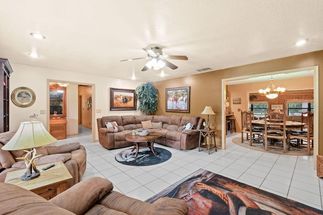 tiled living room with ceiling fan with notable chandelier