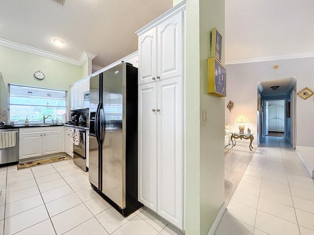 kitchen with sink, ornamental molding, appliances with stainless steel finishes, light tile patterned floors, and white cabinets