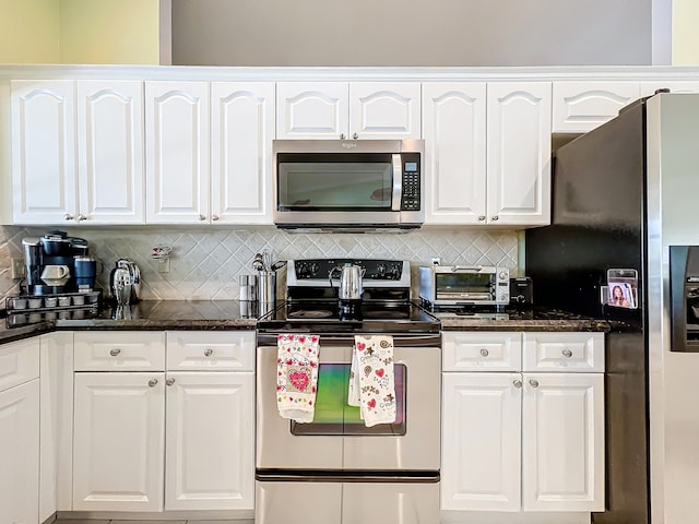 kitchen featuring backsplash, stainless steel appliances, white cabinets, and dark stone countertops