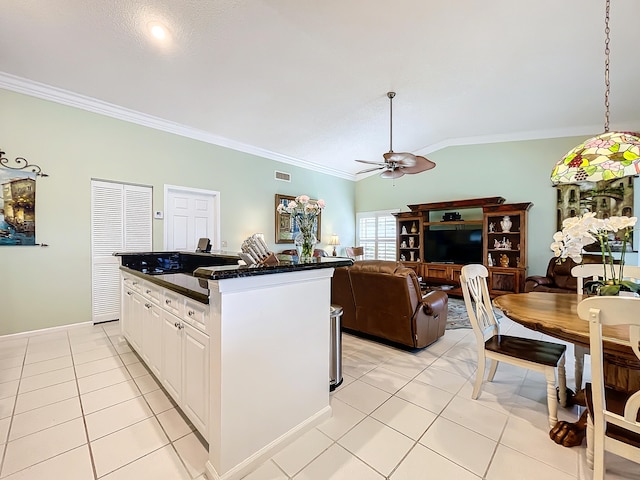 kitchen featuring ceiling fan, white cabinets, vaulted ceiling, and light tile patterned flooring