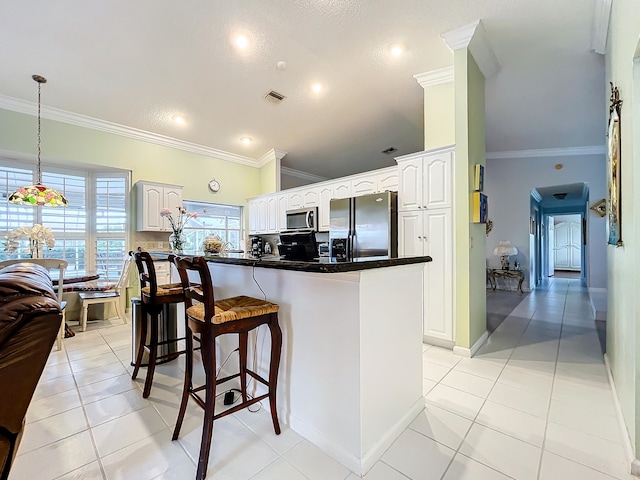 kitchen with appliances with stainless steel finishes, white cabinetry, ornamental molding, pendant lighting, and light tile patterned flooring