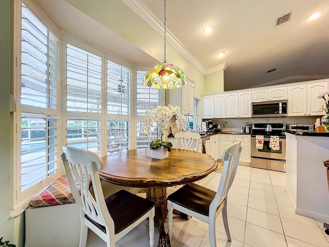 tiled dining room with vaulted ceiling and ornamental molding