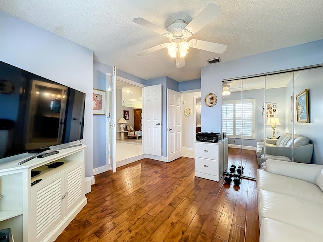 living room with ceiling fan, a textured ceiling, and wood-type flooring