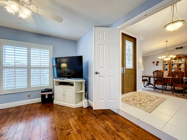 interior space featuring a textured ceiling, ceiling fan with notable chandelier, hardwood / wood-style floors, and ornamental molding